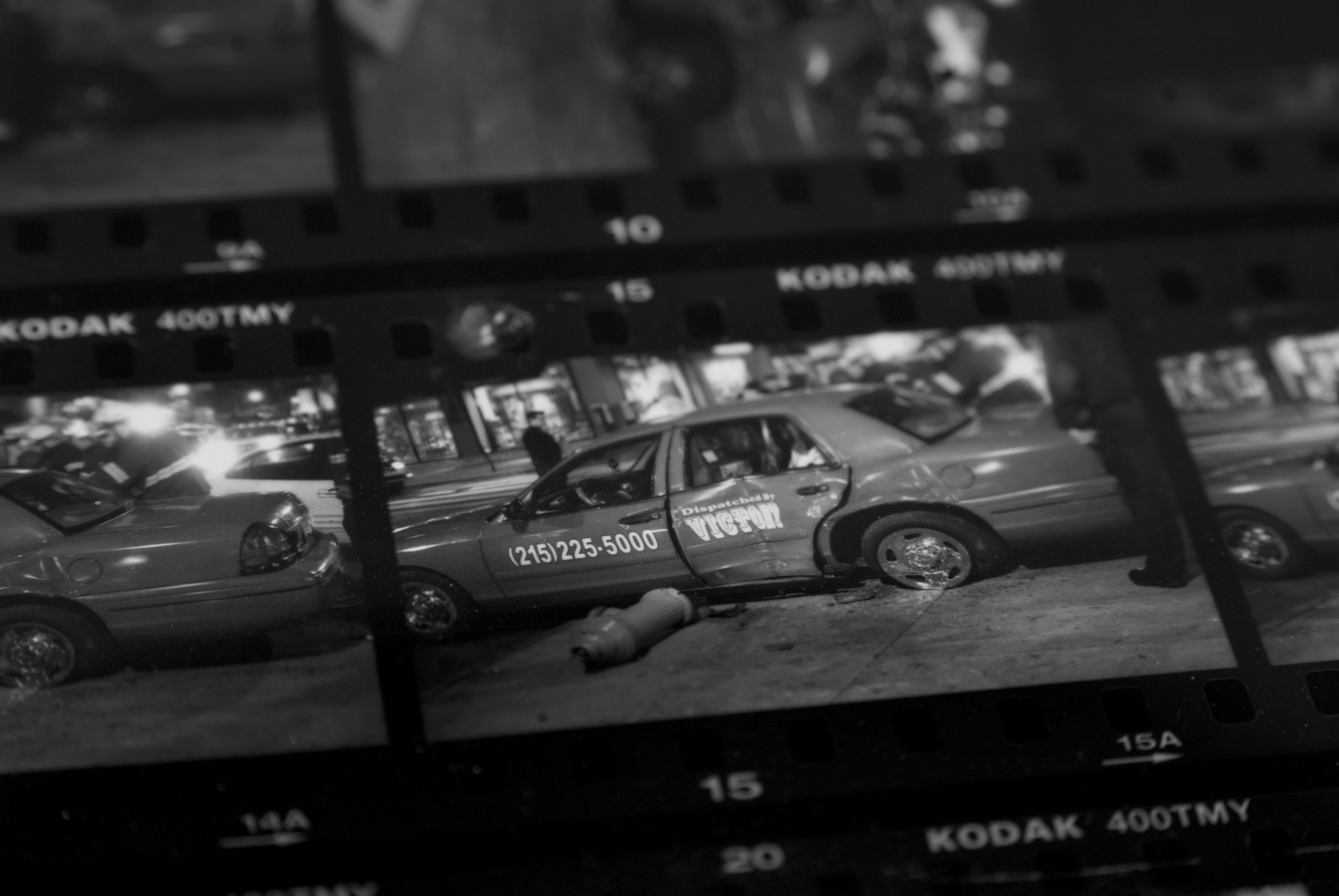 Macro photograph of a contact sheet from film photography. The frame shows a taxi car accident.